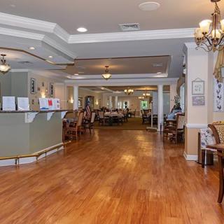 A spacious lobby with hardwood flooring, a reception desk, and seating areas under elegant chandeliers.