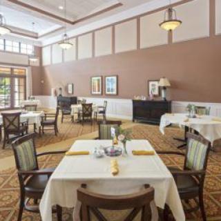 An elegant and spacious dining area with neatly arranged tables and chairs, featuring warm lighting and classic decor.