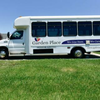 A white shuttle bus parked on a grassy area under a clear sky.