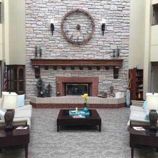 A cozy living room with a stone fireplace, large clock, and comfortable seating arrangement.