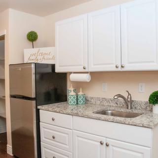 A modern kitchen with white cabinets, granite countertops, and stainless steel refrigerator.