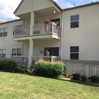 A residential apartment building with two balconies overlooking a well-maintained lawn.