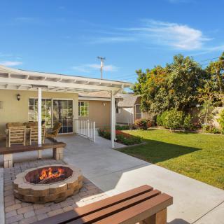 A cozy backyard with a fire pit, patio seating, and a lush lawn.