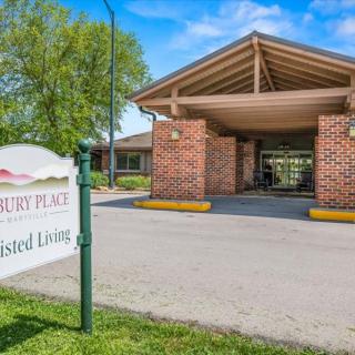 Entrance to an assisted living facility with a sign and brick pillars.