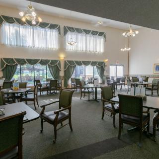 A spacious dining room with elegant furniture and large windows adorned with curtains.