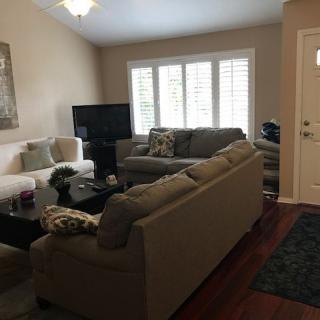 A cozy living room with sofas arranged around a coffee table and a TV near the window.