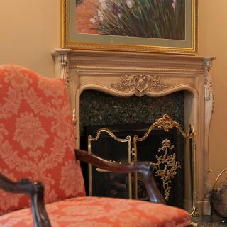 An elegant interior with a classic armchair and ornate fireplace.