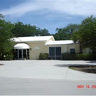 A residential house with a driveway and surrounding trees under a clear sky.