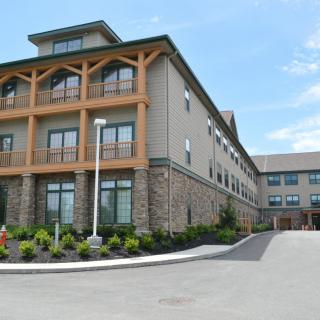 A modern hotel building with a landscaped exterior and clear sky.