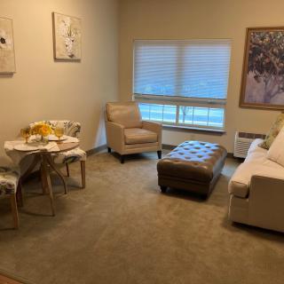 A cozy living room with a sofa, armchair, and a small dining table.