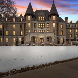 A majestic castle-like historic building illuminated against a vibrant sunset with a snowy foreground.