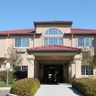 A two-story residential building with a main entrance and surrounding landscaping.