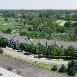 Aerial view of buildings surrounded by trees and a parking lot.