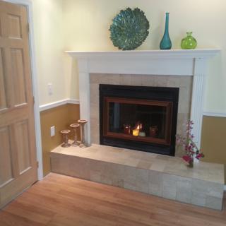 A cozy living room corner featuring a lit fireplace with decorative items on the mantel.
