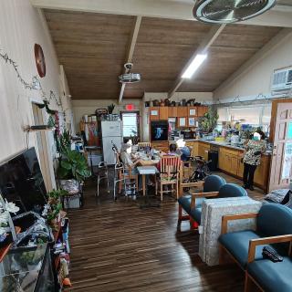 A cozy open-plan living area featuring a kitchen and dining space with wooden flooring and ceiling decor.