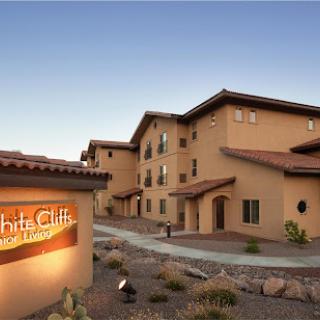 A picturesque view of the White Cliffs resort at sunset, showcasing its unique architectural design against a serene desert backdrop.