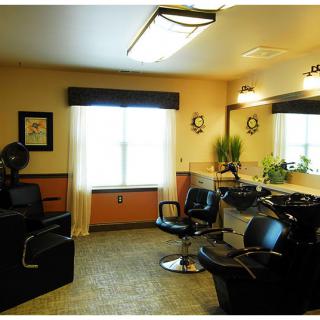 A cozy interior of a hair salon with chairs and mirrors, featuring soft lighting and a window.