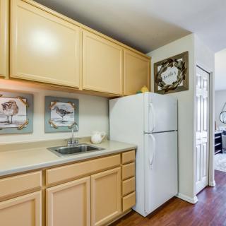 A cozy kitchen featuring light wood cabinets, a white refrigerator, and decorative wall art.