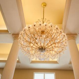 A luxurious chandelier hanging from the ceiling, surrounded by elegant columns.