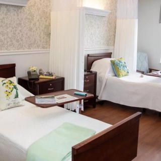 A clean and well-organized hospital room with two beds, each adorned with pillows, in a medical facility.
