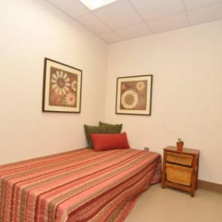 A small, minimalist bedroom with a single bed and decorative artwork on the walls.