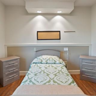 A serene and minimalist bedroom featuring a neatly made bed, stylish nightstands, and soft lighting.