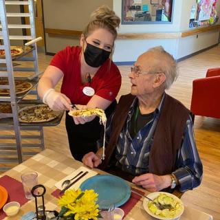 A caregiver assists an elderly man during meal time at a nursing home.