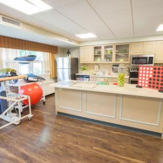 A modern kitchen space designed for rehabilitation, featuring an exercise ball and accessible appliances.