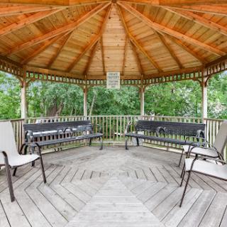 A serene gazebo with wooden beams and seating, perfect for outdoor relaxation.