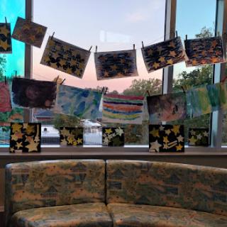 A vibrant display of children's artwork hanging by the window, creating a warm and inviting atmosphere.