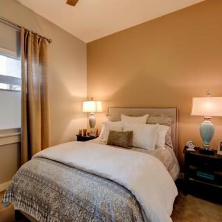 Cozy bedroom with a neatly made bed, warm lighting, and elegant decor.