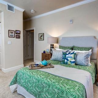 A cozy and modern bedroom featuring green bedding with decorative pillows and a stylish decor.