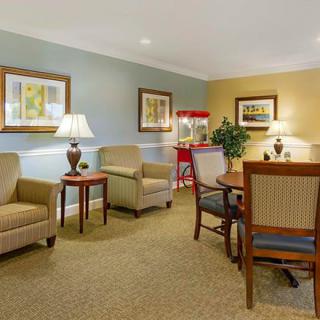 A cozy living room with comfortable chairs, lamps, and a popcorn machine for entertainment.
