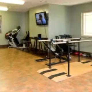 A physical therapy room equipped with parallel bars and exercise machines.