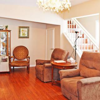A cozy living room with brown recliner chairs, a wooden floor, and a staircase leading to the upper level.