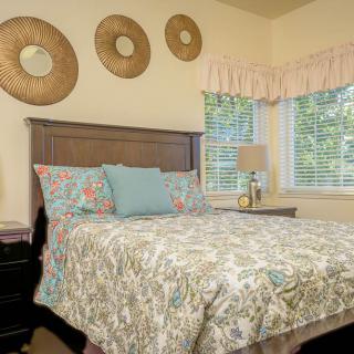 A cozy bedroom with decorative wall hangings and a comfortably made bed.