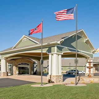 The entrance of a hotel showcasing the American and state flags against a clear blue sky.