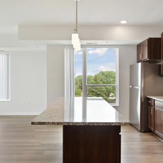 A modern kitchen with a large island, stainless steel appliances, and bright natural lighting.