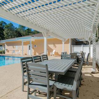 Outdoor poolside seating area with pergola shade on a sunny day.