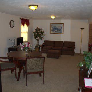 A cozy living room with a brown sofa, dining table, TV, and decorative elements.