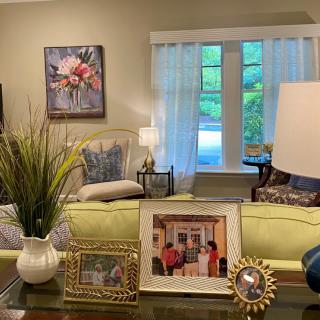 A cozy living room with a sofa, coffee table adorned with family photos, and elegant decor.