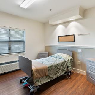 A clean and modern hospital patient room equipped with a bed and essential amenities.