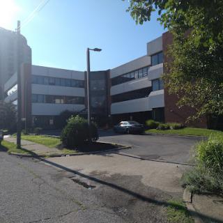 A modern commercial building surrounded by greenery on a sunny day.