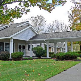 A charming residential house with a covered entrance and well-maintained landscaping in an autumn setting.