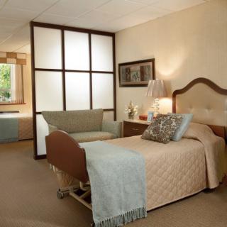 A cozy and well-decorated hospital room with a single bed and a small sofa.