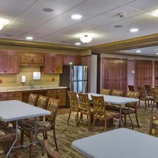 A spacious community dining room with tables, chairs, and a kitchen area.