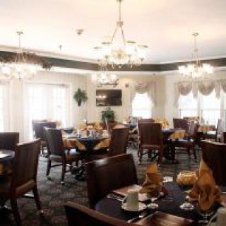 A well-lit dining area featuring elegant chandeliers and neatly arranged tables with chairs.