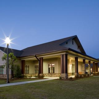 A modern building illuminated during the evening with a clear sky backdrop.