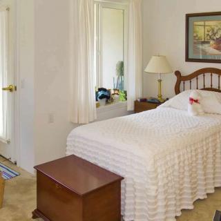 A cozy bedroom with a single bed, bedside lamp, and a mirror on the wall.