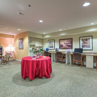 A well-lit office space with multiple workstations and a table covered with a red cloth.